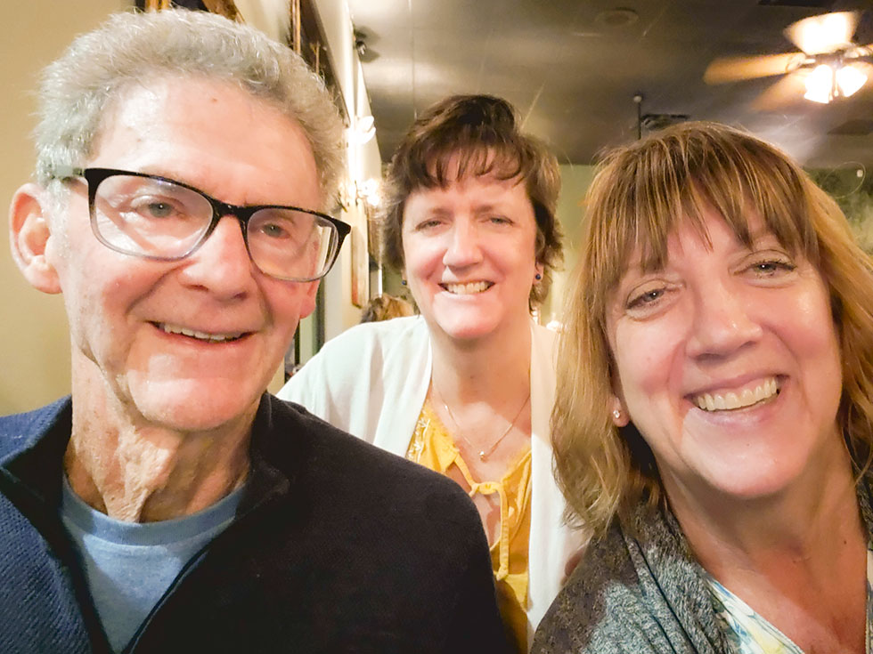 two women and older man smiling at camera