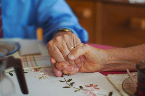 NOlder couple holding hands at table