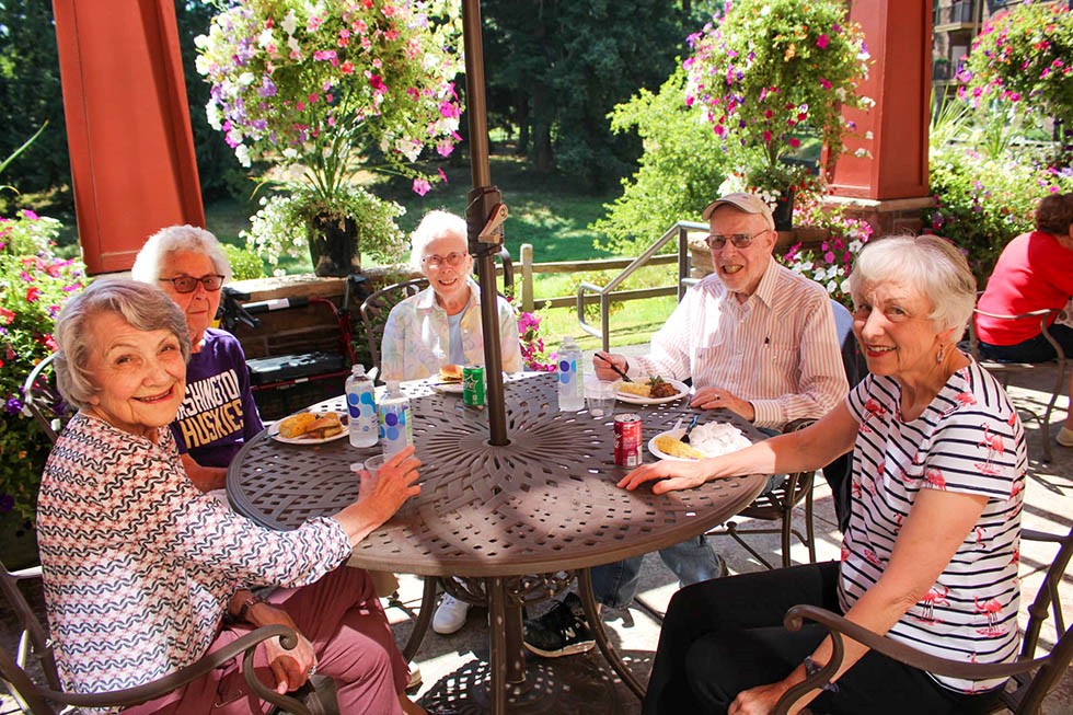 a group of friends enjoying some food outside on a porch