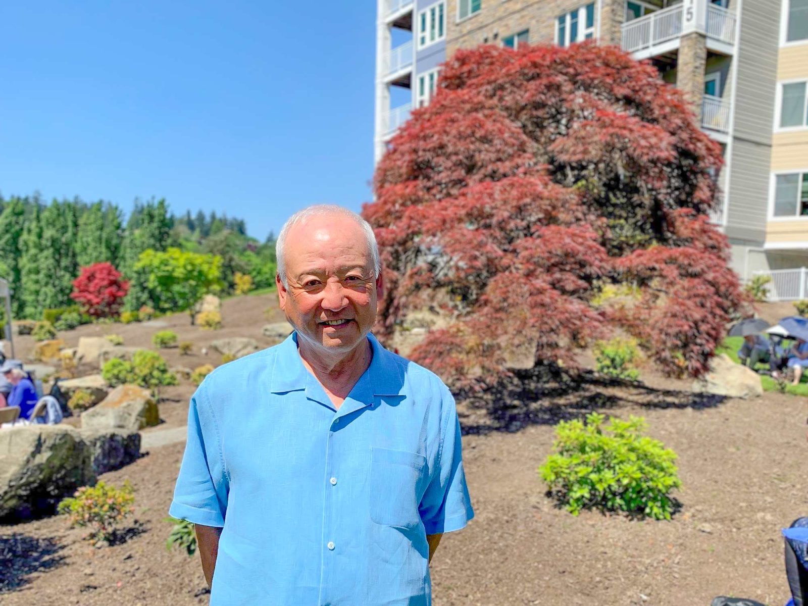 Allan Kubota standing in front of the Meditation Garden at Wesley Des Moines