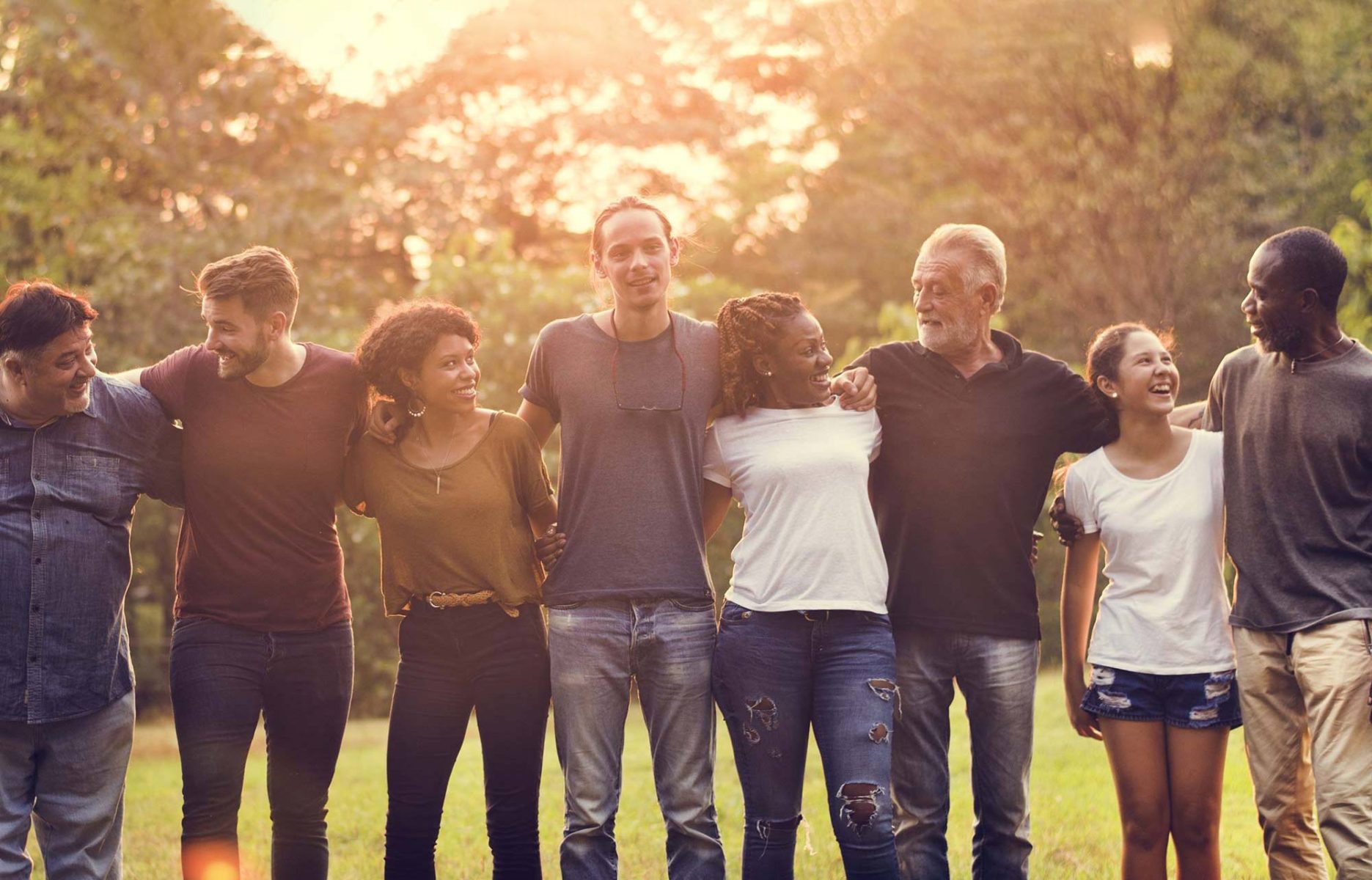 Diverse group of people holding hands outdoors at a park with the sun shining